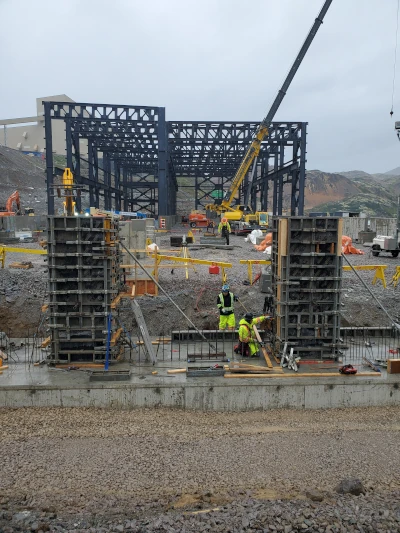 heavy duty truck shop under construction, steel frame standing, excavator and crew at work