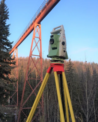 artistic shot of survey equipment under bridge with mountain in the background