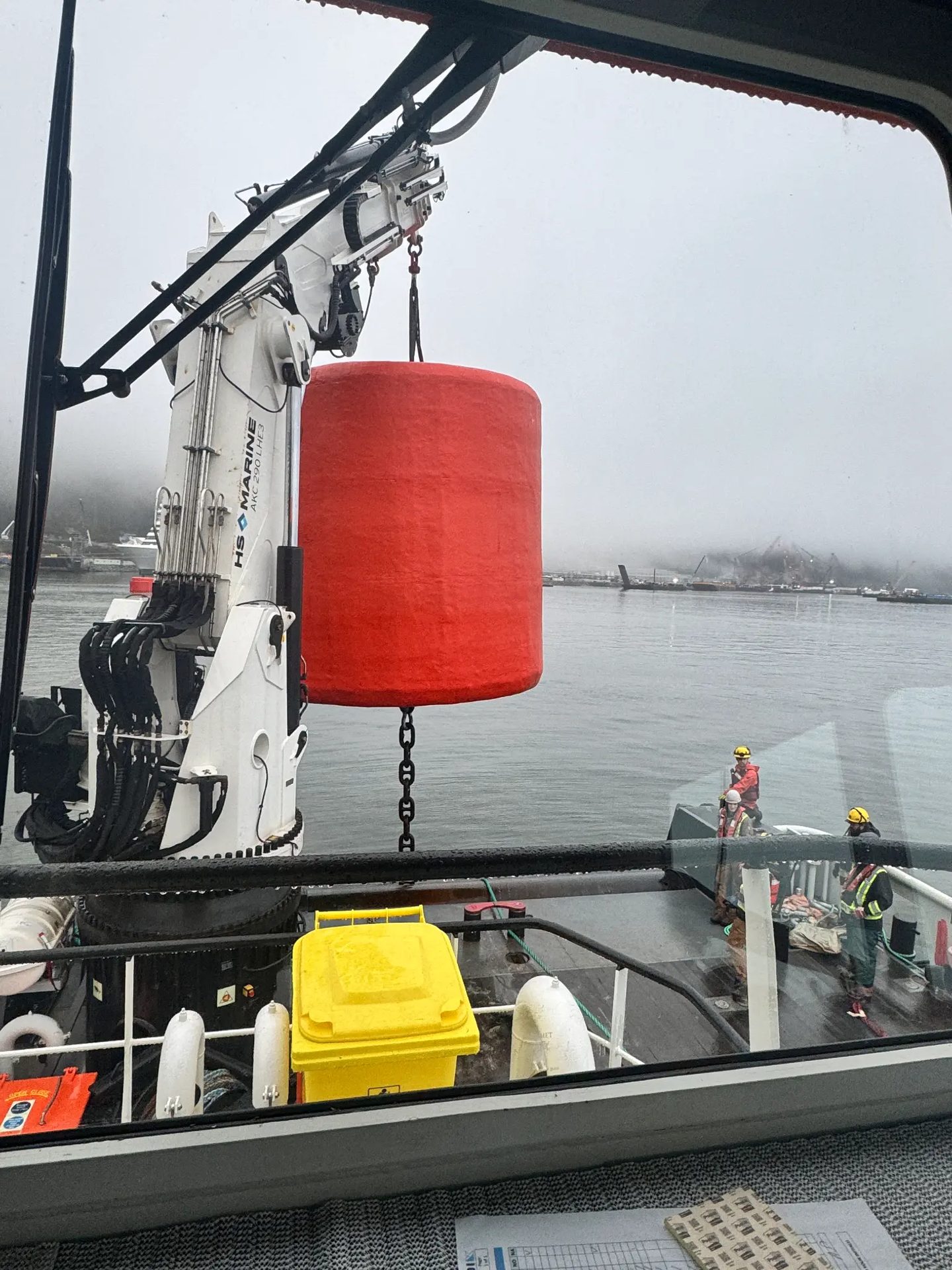 Red anchor buoy being lifted by crane at Woodfibre LNG