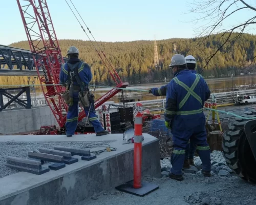 Crew working with crane on construction site overlooking an inlet