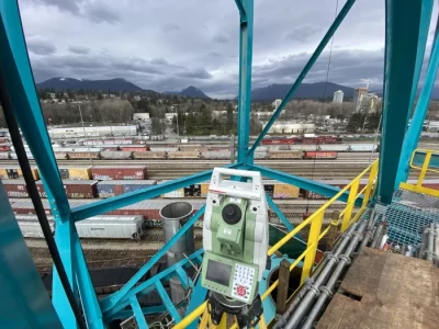 with mountains in the distance, a railyard is surveyed from high up on a steel structure